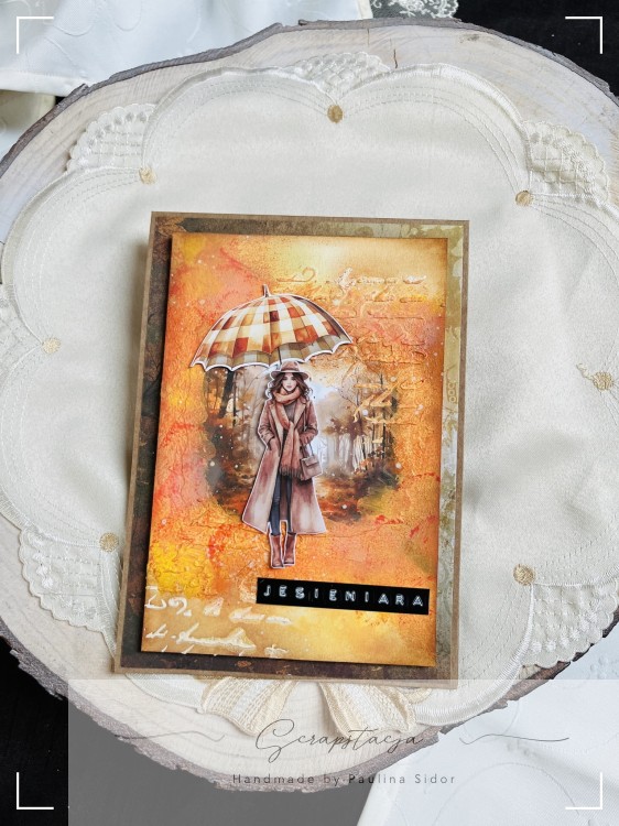 Kartka handmade „Jesieniara” z jesienną ilustracją kobiety z parasolką w ciepłych odcieniach pomarańczu, żółci i czerwieni. Projekt sezonowy od Scrapstacja.