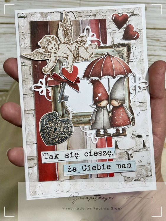 Romantyczna kartka walentynkowa handmade z postaciami pod parasolem, sercami i napisem „Tak się cieszę, że Ciebie mam”.
