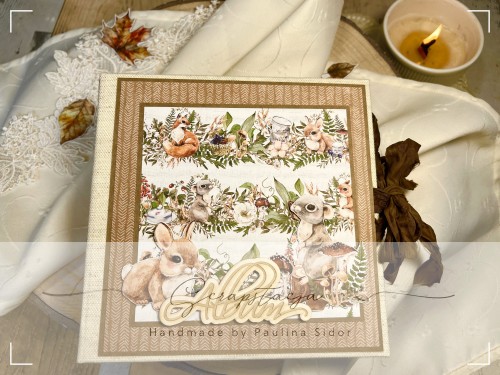 Zdjęcie przedstawia okładkę albumu wykonanego ręcznie metodą scrapbookingu w leśnym klimacie. Okładkę stanowi grafika z leśnymi zwięrzątkami i dużym napisem Album. Album zamykany na wstążkę gnieciuszkę.
