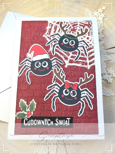 Kartka świąteczna z pająkami i napisem „Cudownych Świąt” na czerwonym tle