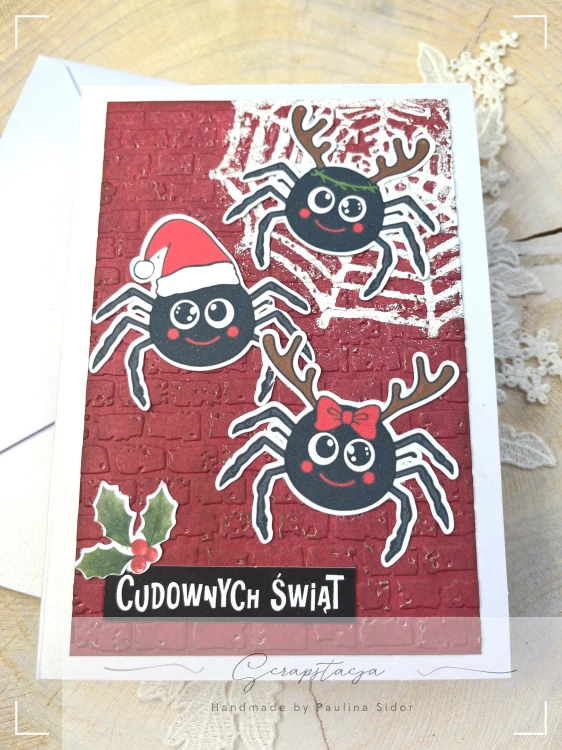 Kartka świąteczna z pająkami i napisem „Cudownych Świąt” na czerwonym tle